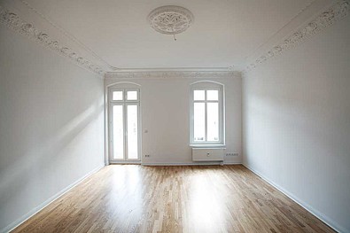 Blick in ein modernisiertes Zimmer mit Balkon und Parkett.